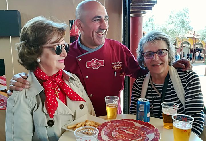 Dos visitantes posan junto al maestro cortador Jesús González Léon