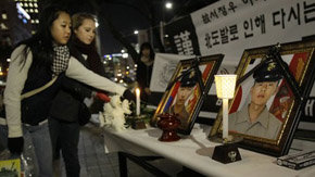 Dos jóvenes depositan flores, en un monumento improvisado de la Infantería de Marina de Corea del Sur

