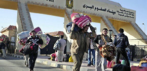 Unos ciudadanos egipcios llevan encima sus pertenencias mientras abandonan Libia a través del paso fronterizo de Al Salum