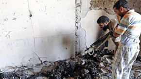 Rebeldes contemplan los cadáveres carbonizados de insurgentes a las afueras de Trípoli.