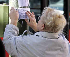 Una mujer pega en una farola un aviso de búsqueda de empleo