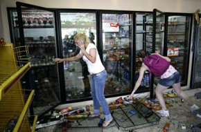 Varias personas observan los destrozos ocasionados en una estación de servicio en Buenos Aires.