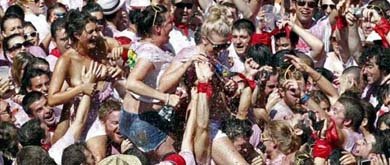 Varios jóvenes aúpan a tres chicas, minutos antes del chupinazo, mientras la turba trata de manosearlas. (EFE)