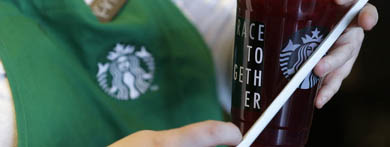 Una empleada de la cadena de cafeterías Starbucks sostiene un vaso con el lema de la campaña 'Race Together' 