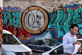 Un hombre camina delante de un graffiti que pone '0 euros' en Atenas 