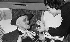 En la imagen de archivo de los años 60, una azafata enciende solícita, un cigarro habano a un pasajero de primer clase. 