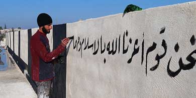 Un miliciano del Estado Islámico escribe en un muro de la ciudad siria de Raqqa 'Somos gente a la que Dios ha honrado con el Islam'. 