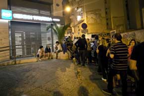 Varios ciudadanos griegos hacen cola delante de un cajero por la noche 