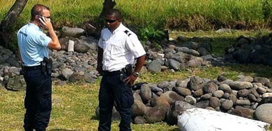 Policías frente a la pieza de dos metros de largo hallada en isla Reunión, en el Índico 