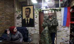 Un retrato de Assad y una bandera rusa en una tienda de ropa militar en Latakia, Siria, el 19 de diciembre de 2015 (AFP / YOUSSEF KARWASHAN)