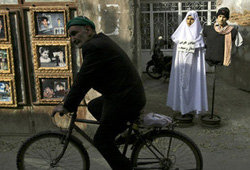 Un iraní en bicicleta cruza delante de una mujer vestida según la ley coránica