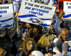 Manifestantes con banderas israelíes y pancartas donde se lee ?Amamos el Ejército, liberen a Elor', durante la manifestación de la noche del martes en Tel Aviv. 