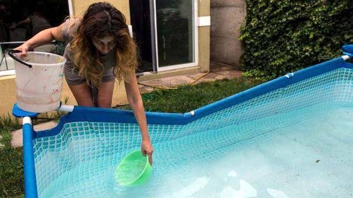 Una mujer recolecta agua de su piscina en Santiago de Chile. 