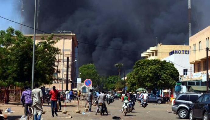 La gente mira como se eleva el humo negro tras los ataques múltiples ocurridos en la capital de Burkina Faso. 
