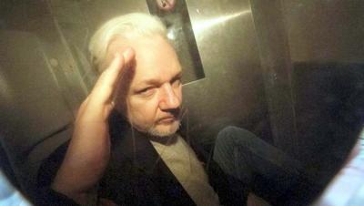 Julian Assange hace un gesto de saludo a los periodistas al salir del tribunal