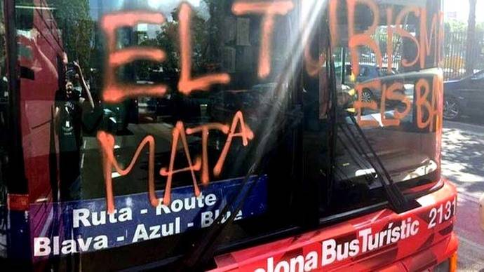 Imagen del bus turístic con la pintada 'El turismo mata los barrios'