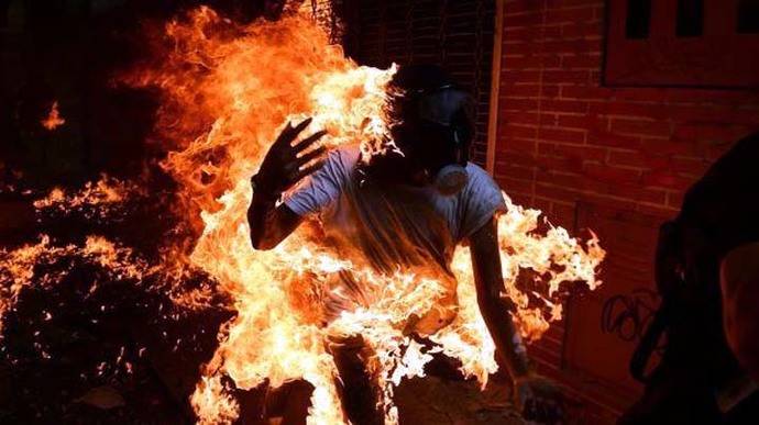 Un opositor se prende en llamas luego de lanzar una bomba lacrimógena en una protesta en la capital de Venezuela
