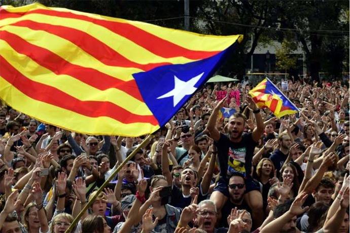 La gente grita consignas mientras agitan banderas catalanas pro-independencia durante una protesta, luego de que cientos de personas resultaran heridas en una represión policial.