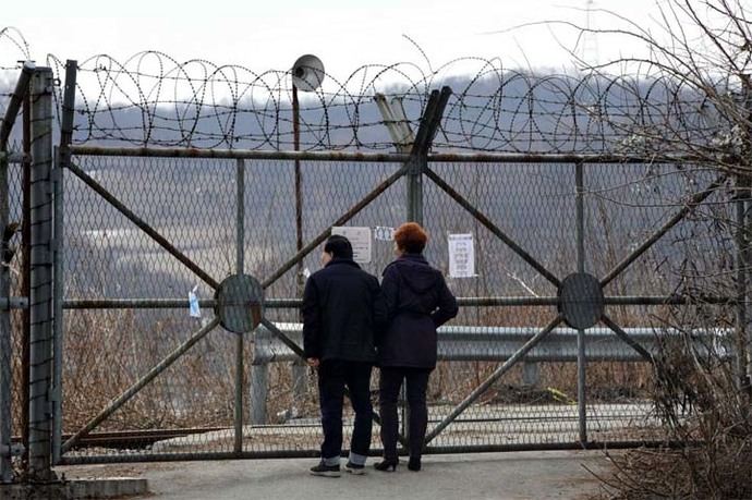 Una pareja se para frente a una valla militar cerca de la Zona Desmilitarizada (DMZ) que divide las dos Coreas.
