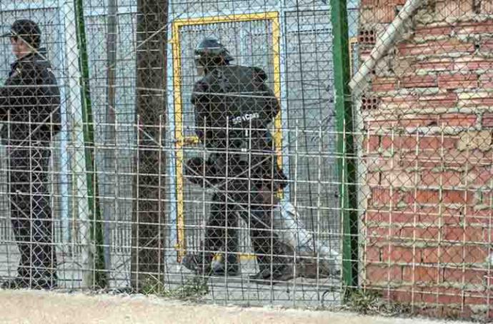  Un agente de la Policía Nacional arrastra a un inmigrante herido al otro lado de la valla de Melilla./ Blasco de Avellaneda