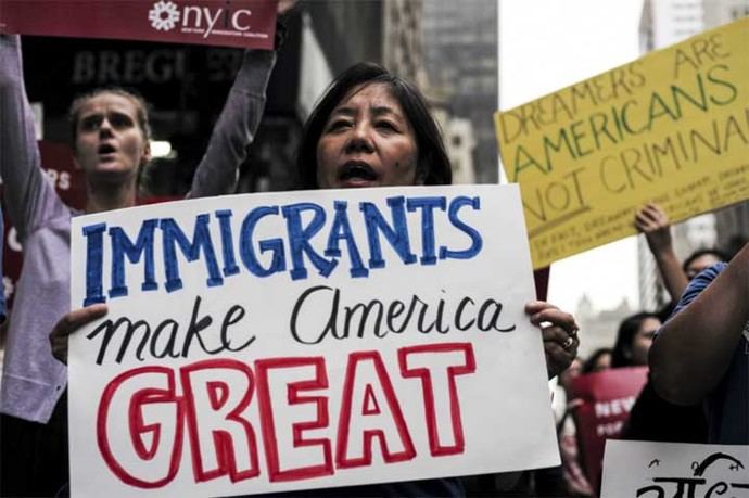 Una manifestante con un cartel que dice 'los inmigrantes hacen grande a América', refiriéndose al slogan de campaña de Trump: Make America Great Again.