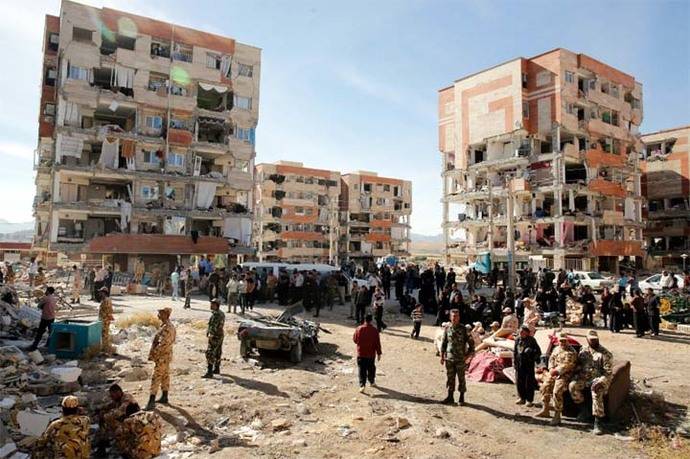 Víctimas del fuerte terremoto de 7,3 grados en la escala de Richter que asoló la provincia de Kermanshah permanecen junto a edificios dañados en la ciudad de Pole-Zahab (Irán)