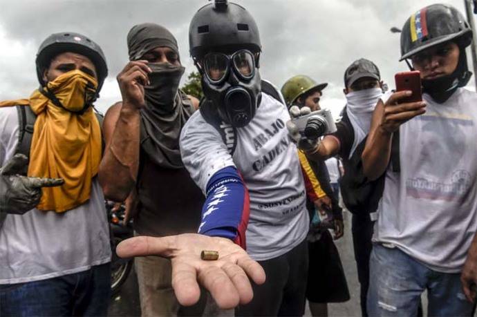 Activistas de la oposición muestran un casquillo de bala durante una manifestación contra el gobierno del presidente Nicolás Maduro a lo largo de la carretera de Francisco Fajardo en Caracas.