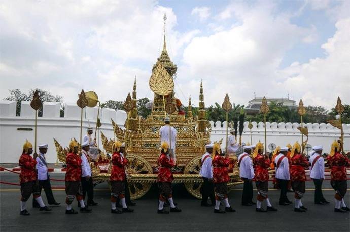 Soldados con uniformes tradicionales arrastran la gran carroza dorada con la urna real del difunto monarca Bhumibol Adulyadej. 