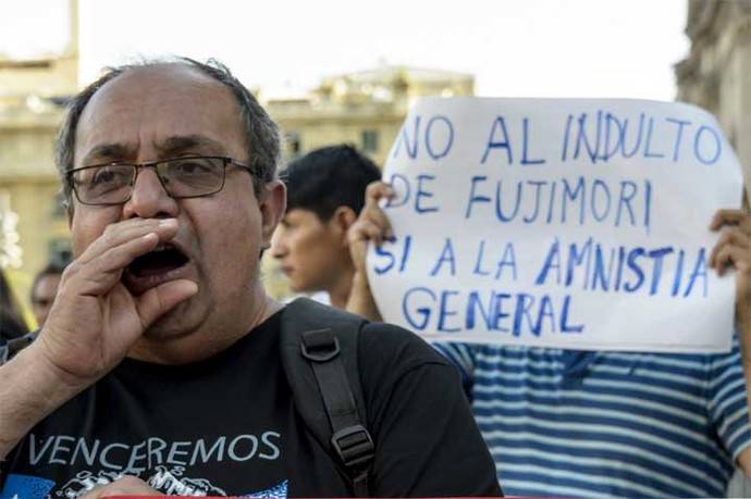 Una manifestante sostiene una bandera de Perú con un mensaje contra el indulto otorgado al expresidente Alberto Fujimori. 