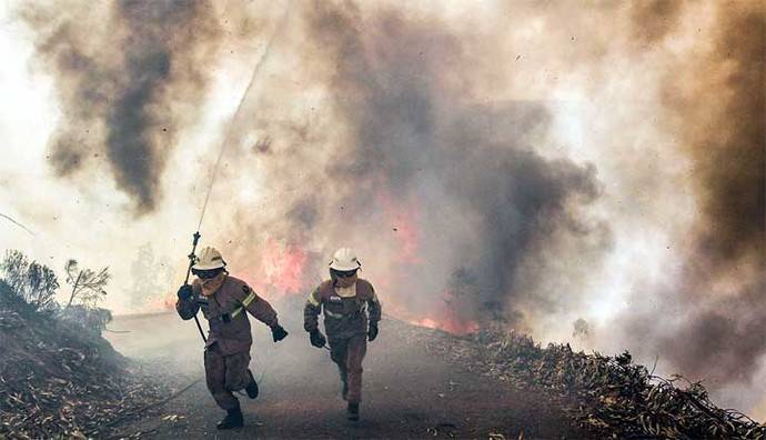 Dos bomberos huyen del fuego en los incendios de Portugal