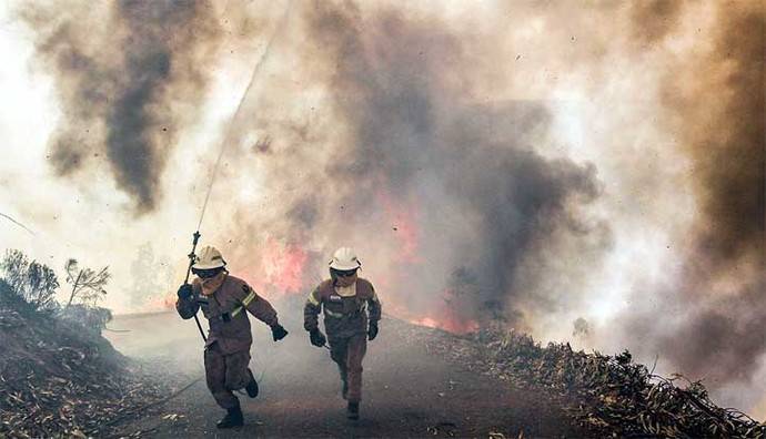 Dos bomberos huyen del fuego en los incendios de Portugal