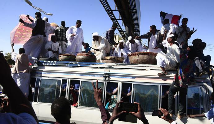 Manifestantes sudaneses en el techo de un autobús