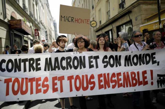Manifestantes sostienen una pancarta que dice "contra Macron y su mundo, todos juntos" en París, Francia.