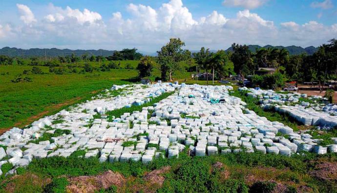 Miles de botellas de agua donadas, aparecen en una finca