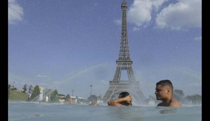 n grupo de personas se refresca en una fuente en París, Francia. 
