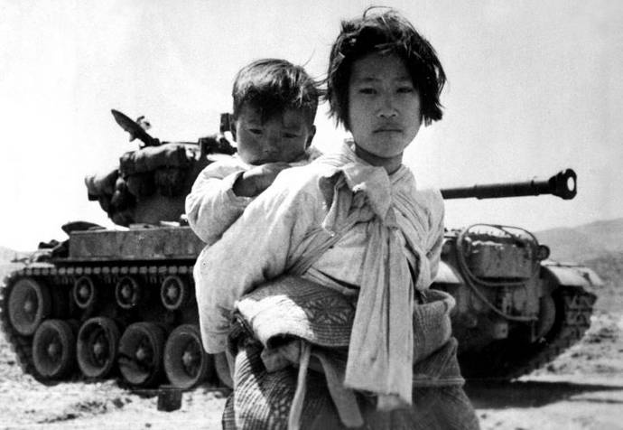 Korean girl walking past a tank, at Haengju, in the Korean War 1951