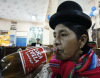 Una mujer aimara bebe una botella de Coca-Colla