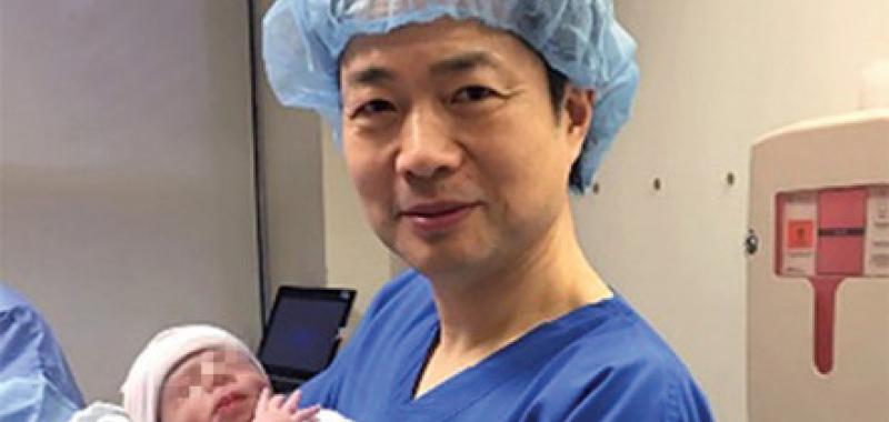 John Zhang sostiene al bebé en el momento de su nacimiento / New Scientist 